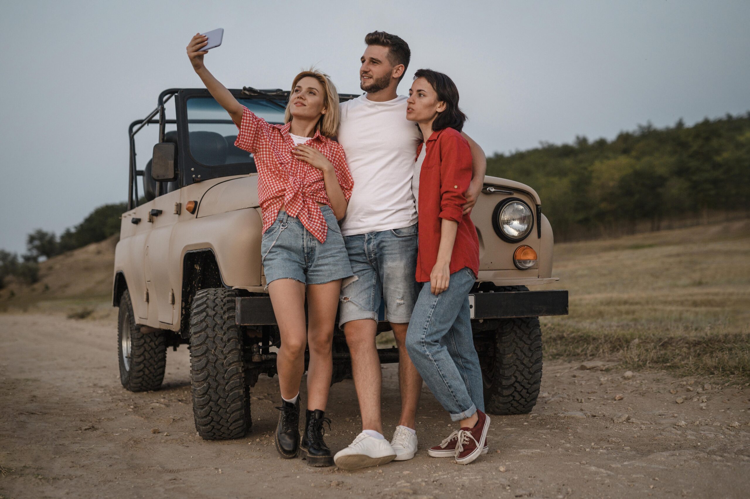 three friends taking selfie with smartphone while traveling by car scaled